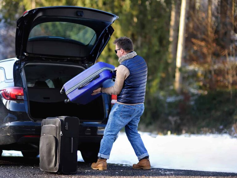 Mężczyzna pakuje bagaże do samochodu przed wyjazdem na urlop